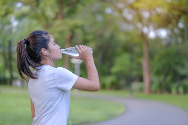 Genç fitness kadın sabah yolun dışında Asya atlet koşu ve egzersiz patika üzerinde çalışan park açık, kadın Çalıştırıcısı'nda yürüyüş sırasında enerji su içme. Spor ve sağlık kavramı
