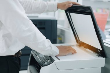 Bussiness man Hand putting a document paper into printer scanner or laser copy machine in office clipart