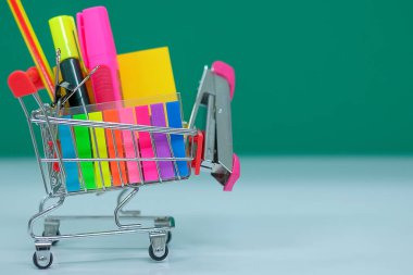 Geri okul ve eğitim kavramları alışveriş sepeti, kalem, zımba, vurgulayıcı ve Not defteri ile