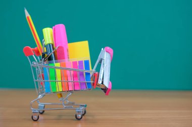 Geri okul ve eğitim kavramları alışveriş sepeti, kalem, zımba, vurgulayıcı ve Not defteri ile