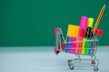 Geri okul ve eğitim kavramları alışveriş sepeti, kalem, zımba, vurgulayıcı ve Not defteri ile