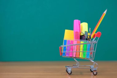 Geri okul ve eğitim kavramları alışveriş sepeti, kalem, vurgulayıcı ve Not defteri ile