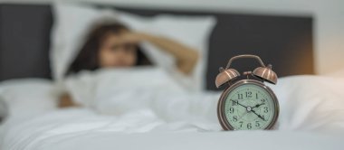 Asyalı kadın ile retro çalar saat, evde yatak odasında genç kadın uyku gece geç saatte yatakta yatan. uykusuzluk uyku, endişeli ve kavramlar vurguladı