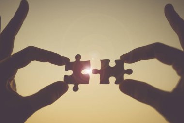 Siluet kadın el çift bağlama gündoğumu etkisi, jigsaw günbatımı arka plan ile tutarak işkadını karşı parça puzzle. İş çözümleri, hedef, başarı, hedefleri ve strateji kavramları