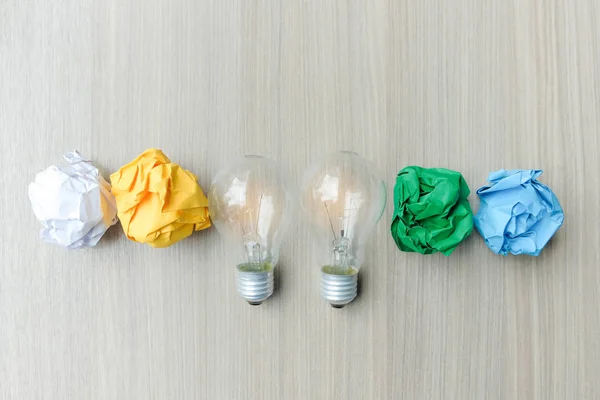 light bulb or lamp with colorful crumpled paper on wooden table. New Idea, Creative, Genius and Innovation concepts