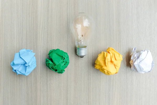 light bulb or lamp with colorful crumpled paper on wooden table. New Idea, Creative, Genius and Innovation concepts