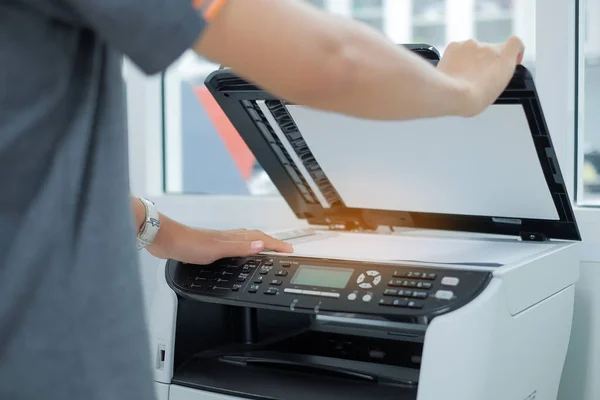 在办公室里把一张文件纸放进打印机扫描仪或激光复印机里 — 图库照片