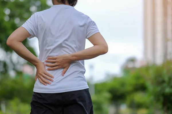 彼のスポーツの傷害 筋肉トレーニング中に痛みを伴うを保持している若いフィットネス女性 アジアのランナーがランニングと運動後背中脇腹の痛みや問題を持つ夏の外 — ストック写真
