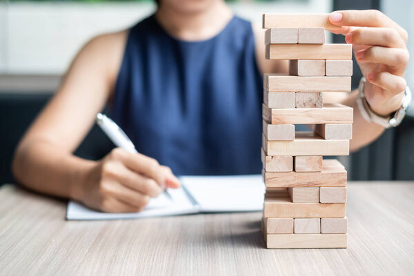 Businesswoman hand placing or pulling wooden block on the tower. Business planning, Risk Management, Solution and strategy Concepts