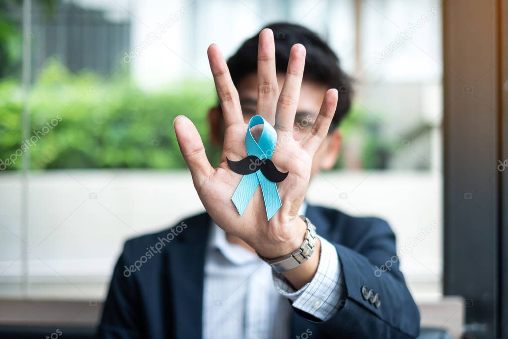 Prostate Cancer Awareness month, Business Man holding light Blue Ribbon with mustache for supporting people living and illness. Men Healthcare and World cancer day concept