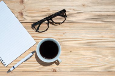 Office ile siyah kahve sağlar; mavi ahşap masa arka plan üzerinde kalem, defter ve gözler gözlük. Kopya alanı ile üstten görünüm