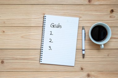 Defter, kalem ve ahşap arka plan üzerinde siyah kahve. İş ve rahatlatıcı kavramları