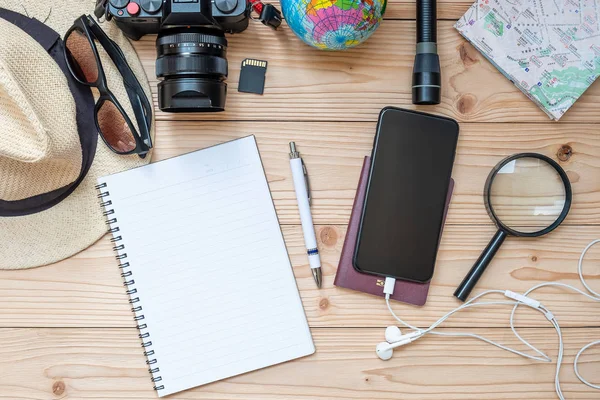 旅行計画のコンセプトの背景 旅行者の付属品 マップ カメラ パスポート 懐中電灯 スマート携帯電話 サングラス 木製のテーブルの上にペンとノート トップ — ストック写真