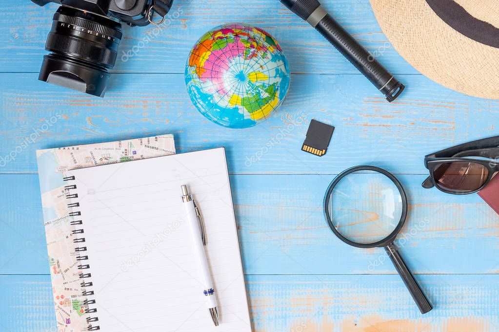 Travel planning concept background. Traveler's accessories; Map, Camera, Passport, Flashlight, Magnifying, smart Phone, Sunglasses, Hat and Notebook on blue  wooden table, Top view and copy space