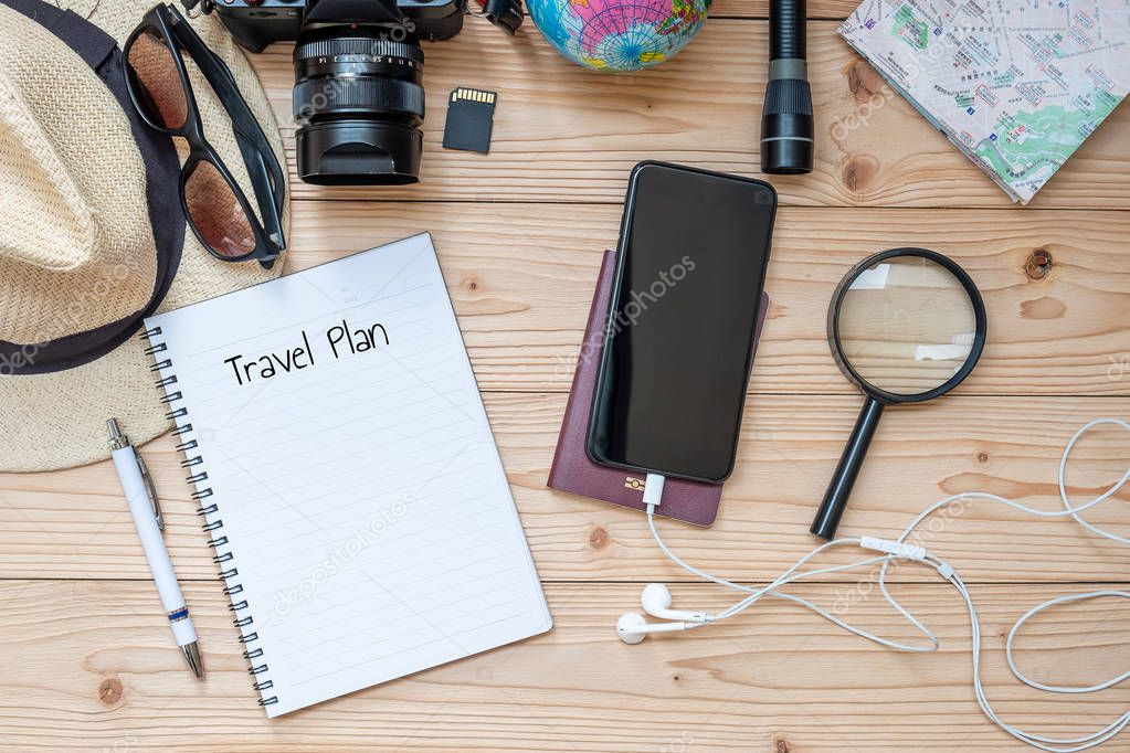 Travel planning concept background. Traveler's accessories; Map, Camera, Passport, Flashlight, Magnifying, smart Phone, Sunglasses, Hat and Notebook with Pen on wooden table, Top view and copy space