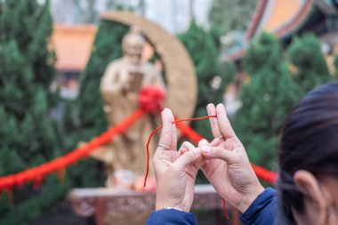 Genç kadın kırmızı ip bağlar ve dua Yue Lao (evlilik tanrısı) Wong Tai Sin Temple içinde aşk ve evlilik dualar cevap için tanınmaktadır. işareti ve popüler turistik Hong Kong için