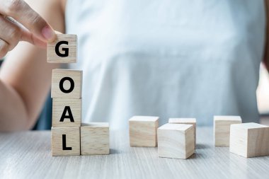 Hedef metin ile ahşap küp tablo arka planda tutan işkadını el. başarı, strateji, çözüm ve iş kavramları