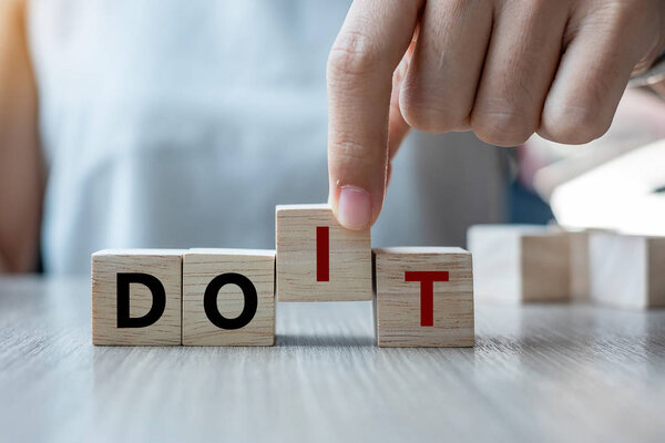Businesswoman hand holding wooden cube with flip over block DON T to DO IT word on table background. success, strategy, solution, business and Positive thinking concepts