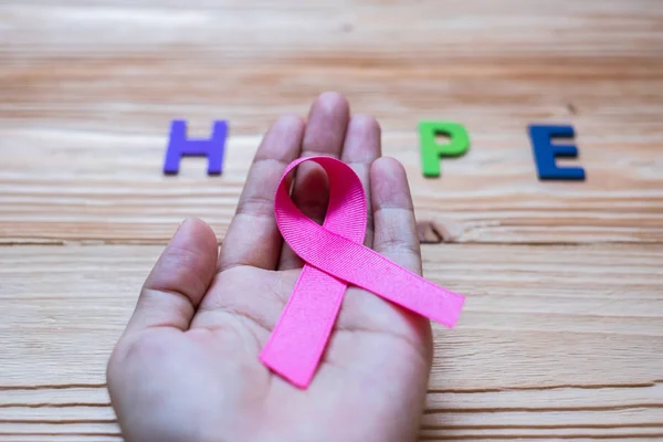 World cancer day (February 4) or Breast cancer, hope letter and pink ribbon on wooden background  for supporting people living and illness. Healthcare and medicine concept