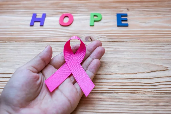 World cancer day (February 4) or Breast cancer, hope letter and pink ribbon on wooden background  for supporting people living and illness. Healthcare and medicine concept