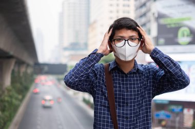 Genç Asyalı adam giyen N95 solunum maskesi korumak ve pm2.5 (partikül madde) trafik ve toz city karşı filtre. Sağlık ve hava kirliliği kavramı