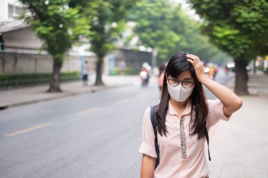 Genç Asyalı kadın giyiyor N95 solunum maskesi korumak ve pm2.5 (partikül madde) trafik ve toz city karşı filtre. Sağlık ve hava kirliliği kavramı