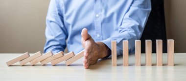 İşadamı el ahşap bloklar durdurma düşen ya da Domino. İş, Risk Yönetimi, çözüm, sigorta ve strateji kavramları