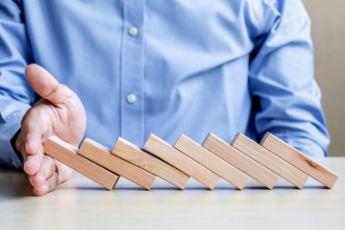 İşadamı el ahşap bloklar durdurma düşen ya da Domino. İş, Risk Yönetimi, çözüm, sigorta ve strateji kavramları