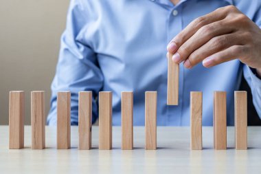 İşadamı el çekerek veya ahşap bloklar veya Domino yerleştirmek. İş, Risk Yönetimi, çözüm ve strateji kavramları