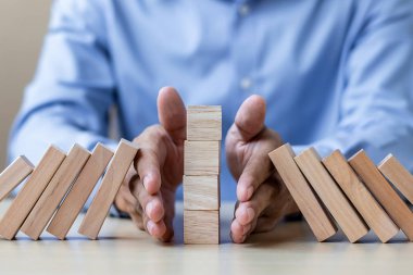 İşadamı el ahşap bloklar durdurma düşen ya da Domino. İş, Risk Yönetimi, çözüm, sigorta ve strateji kavramları