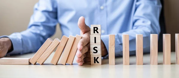 İşadamı el ahşap bloklar durdurma düşen ya da Domino. İş, Risk Yönetimi, çözüm, sigorta ve strateji kavramları