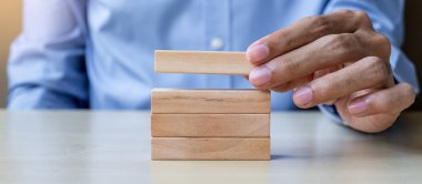 Ahşap yapı taşları tablo arka planda tutan işadamı el. İş planlama, Risk Yönetimi, çözüm ve strateji kavramları