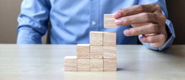 İşadamı, binanın üzerine tahta bloklar yerleştiriyor ya da çekiyor. İş planlaması, Risk Yönetimi, Çözüm ve Strateji Kavramları