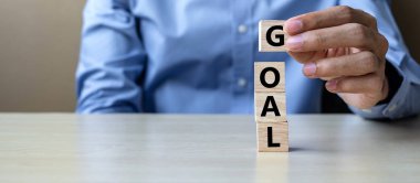 Hedef metin ile ahşap küp tablo arka planda tutan işadamı el. başarı, strateji, çözüm ve iş kavramları