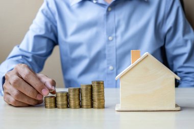İşadamı el büyüyen para merdiven veya yığın ev modeli ile altın madeni para koyarak. İşletme, yatırım, emeklilik planlama, finans ve sigorta kavramı