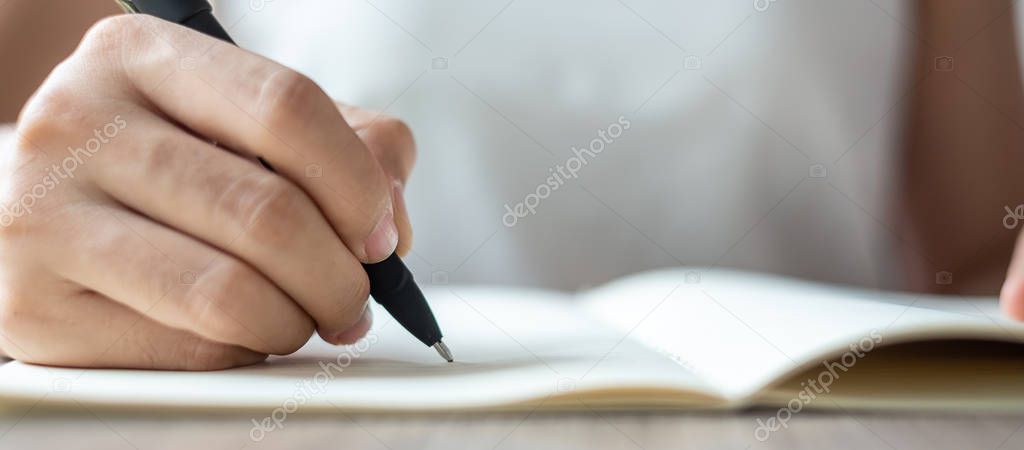 Businesswoman writing on notebook in office, hand of woman holdi