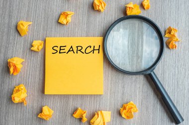 Ufalanmış kağıt ve büyüteç g ile sarı nota üzerinde arama kelimeleri