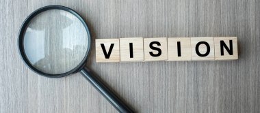 Ahşap masa sırtında vizyon metin ahşap küpler ve büyüteç