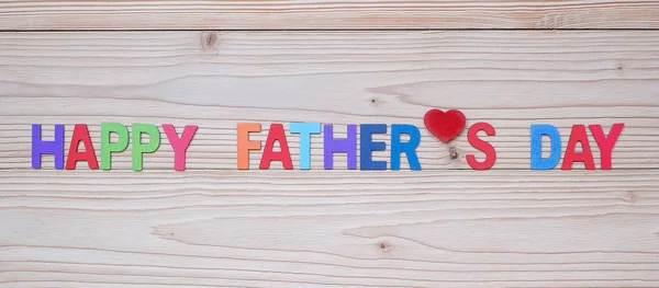 Happy Father\'s Day text with red heart shape on wooden backgroun