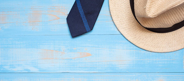 blue necktie with hat on wooden background with copy space for t