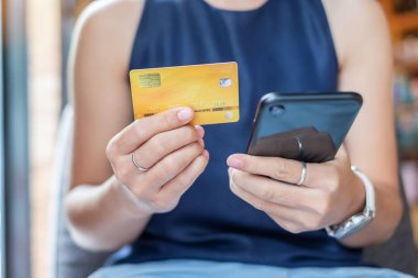 Genç, sıradan bir iş kadını kredi kartı tutuyor ve dokunuşlar kullanıyor.