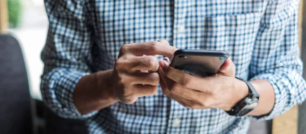 Joven hombre de negocios casual sosteniendo y utilizando el teléfono inteligente para sms me — Foto de Stock