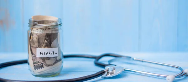 Pot en verre argent et stéthoscope cardiologie sur table en bois bleu ba — Photo