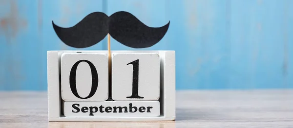 1 September Calendar and mustache on wood table background. Fath