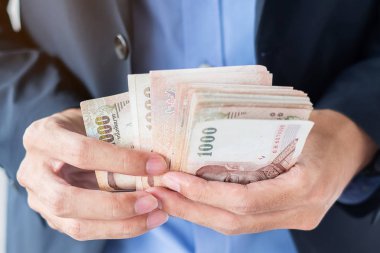 Thai Baht banknot yığınını tutan işadamı el. iş, mon