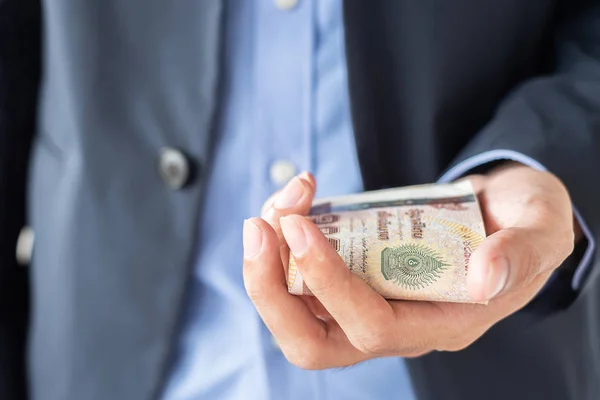 Businessman hand holding Thai Baht banknote stack. business, mon