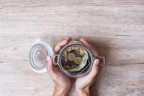 Mano de mujer sosteniendo moneda en frasco de vidrio. día de salvación del mundo, bu —  Fotos de Stock