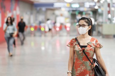 Surat maskesi takan genç Asyalı bir kız Coronavirus 'u koruyor metro istasyonunda yürüyen mutlu bir turist kadın. Sosyal uzaklık, yeni normal ve covid-19 salgınından sonraki yaşam