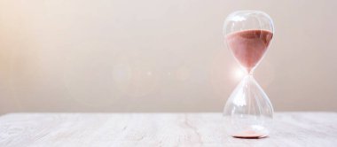 Masadaki kum saati kum saati, geçen zamanı ölçen kum saati ampulünden akıyor. Geri sayım, teslim tarihi, yaşam süresi ve emeklilik kavramı