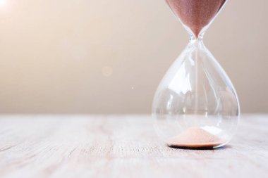 Masadaki kum saati kum saati, geçen zamanı ölçen kum saati ampulünden akıyor. Geri sayım, teslim tarihi, yaşam süresi ve emeklilik kavramı